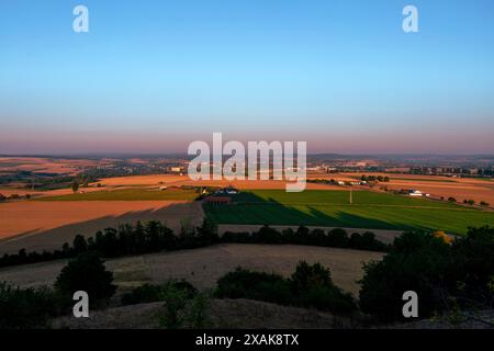 Blick auf die Stadt Warburg an einem Sommermorgen bei Sonnenaufgang, Schatten von der Ruine von Schloss Desenberg im unteren Bilddrittel, Bezirk Höxter, Nordrhein-Westfalen Stockfoto