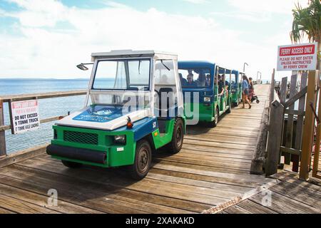 Mit der Straßenbahn werden Touristen auf dem hölzernen Steg der Fähre Kingfisher Bay an der Westküste von Fraser Island (K'gari), Queensland, Australien, abgeholt Stockfoto