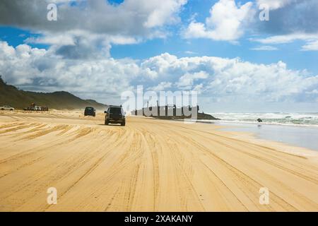 Geländewagen fahren Offroad auf der Strandstrecke von Fraser Island in der Nähe des Schiffswracks SS Maheno, halb im Sand des 75 km langen Strandes im Osten von coa begraben Stockfoto