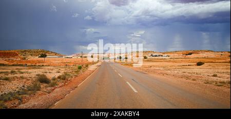 Gerade Autobahn unter bewölktem Himmel in der Nähe der Opalminenstadt Coober Pedy im Outback von South Australia Stockfoto