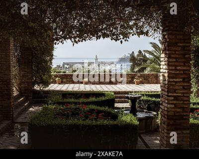 Der Hafen von Malaga, mit einem Kreuzfahrtschiff und dem Leuchtturm La Farola im Sommer, Andalusien, Spanien, vom Garten der Festung Alcazaba aus gesehen Stockfoto