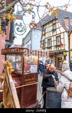 Europa, Frankreich, Grand Est, Elsass, Eguisheim, Mann, der Marronen auf dem Weihnachtsmarkt in Eguisheim verkauft Stockfoto