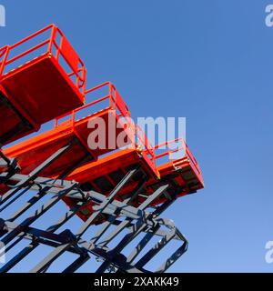 Gruppe von roten Scherenhebern auf einem klaren blauen Hintergrund, perspektivische Aufnahme aus flachem Winkel Stockfoto