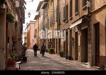 MONTAIONE, ITALIEN - 10. SEPTEMBER 2023 - ein älteres Ehepaar, das am frühen Morgen durch eine leere Gasse von Montaione in der Toskana spaziert Stockfoto