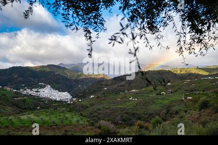 Panoramaaufnahme eines weißen Dorfes, Tolox, typisch für den Naturpark der Sierra de las nieves in Andalusien, bewölkter Tag und Regenbogen im Hintergras Stockfoto