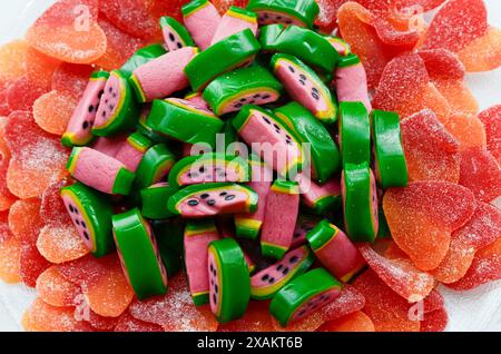 Strukturierte Gelee-Bonbons in Form von Wassermelonenscheiben auf anderen herzförmigen Bonbons mit Zucker. Stockfoto