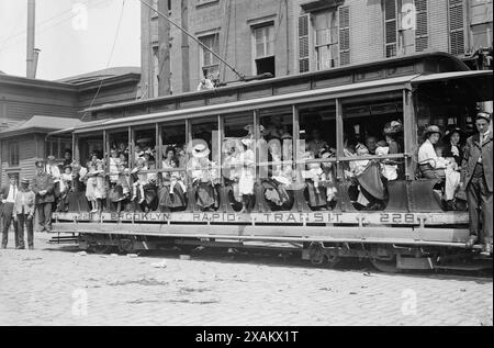 Frischluftausflug, 1913. Wahrscheinlich zeigt sie Mütter und ihre Kinder in einem Trolley-Wagen, der zu einer Fähre fährt, die sie nach Sea Breeze auf Coney Island brachte, auf einer Reise, die vom Fresh Air Home der New York Association gesponsert wurde, um den Zustand der Armen zu verbessern. Stockfoto