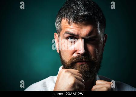 Nahaufnahme Porträt ernster Karate Mann in Kampfposition. Männlicher Karatelehrer mit geballten Fäusten. Muskuläres Fitnessmodell bereit für Karatetraining Stockfoto