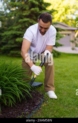 Gärtner pflanzt Pflanzen auf dem Hof. Saisonale Arbeiten im Garten. Landschaftsdesign. Landschaftsgestaltung. Stockfoto