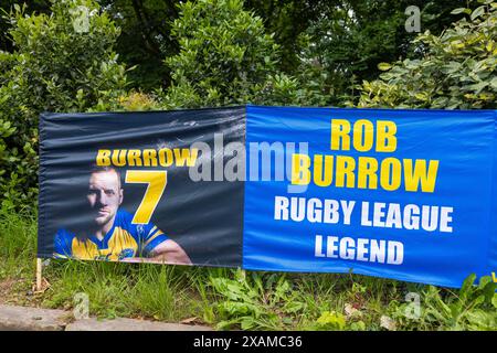 Leeds, Großbritannien. JUNI 2024. Banner, die nach Rob Burrow im Roundhay Park dedidiert wurden, während Läufer sich auf die 7-km-Route vorbereiten, geformt wie ein Nashorn, durch die Straßen von Moor Town zu Ehren der Leeds Rhinos Legende Nummer 7 - die am Sonntag im Alter von 41 Jahren nach einem über 4-jährigen Kampf mit der Motoneurone Disease (MND) starb. Credit Milo Chandler/Alamy Live News Stockfoto