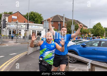 Leeds, Großbritannien. JUNI 2024. Läufer posieren vor der Kamera, während sie an einer 7-Meilen-Route teilnehmen, die wie ein Nashorn geformt ist, durch die Straßen von Moor Town zu Ehren von Leeds Rhinos-Legende Nummer 7 Rob Burrow, der am Sonntag im Alter von 41 Jahren nach einem über vierjährigen Kampf gegen die Motoneurone Disease (MND) starb. Credit Milo Chandler/Alamy Live News Stockfoto