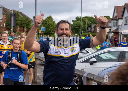 Leeds, Großbritannien. JUNI 2024. Läufer posieren vor der Kamera, während sie an einer 7-Meilen-Route teilnehmen, die wie ein Nashorn geformt ist, durch die Straßen von Moor Town zu Ehren von Leeds Rhinos-Legende Nummer 7 Rob Burrow, der am Sonntag im Alter von 41 Jahren nach einem über vierjährigen Kampf gegen die Motoneurone Disease (MND) starb. Credit Milo Chandler/Alamy Live News Stockfoto