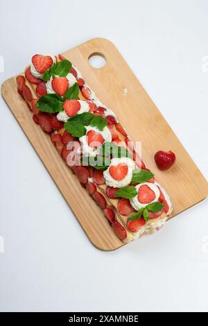 Blick von oben auf frisch zubereiteten Tiramisu-Kuchen mit Erdbeeren und Minzblättern. Heimkochen. Stockfoto