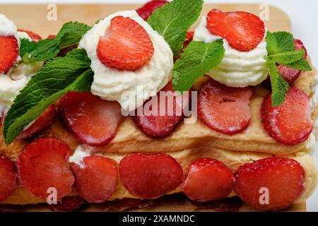 Nahaufnahme eines Teils eines frisch zubereiteten Tiramisu-Kuchens mit Erdbeeren und Minzblättern. Heimkochen. Stockfoto