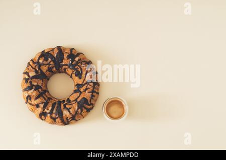 Köstlicher Kuchen mit Schokoladenbelag und Tasse Kaffee auf Pastellcremehintergrund mit Kopierraum. Minimales süßes Dessertkonzept. Stockfoto