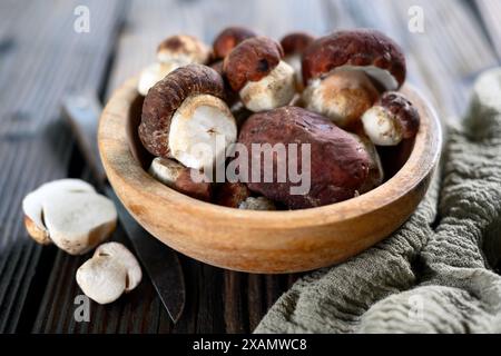 Holzschale mit frischen Wildpilzen und Messer auf rustikalem Holztisch Stockfoto