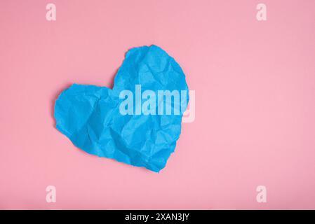 Blau zerknitterte Papierstruktur in Herzform isoliert auf rosa Hintergrund. Das Konzept der Liebe, des Herzschmerzes. Stockfoto