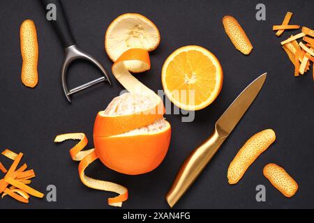Komposition mit frischer Orange, Schale und Messern auf dunklem Hintergrund Stockfoto