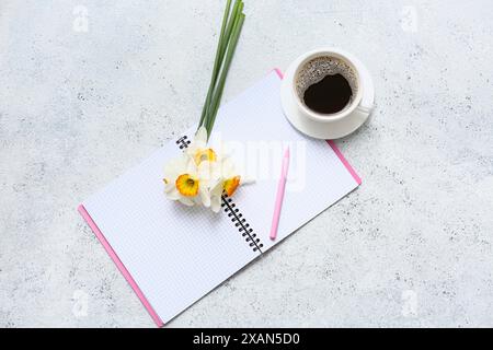Narzissen Blumen mit offenem Notizbuch und Tasse Kaffee Grunge weißen Hintergrund. Draufsicht Stockfoto