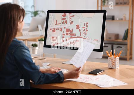 Kartograph arbeitet mit Katasterkarten am Tisch im Büro Stockfoto