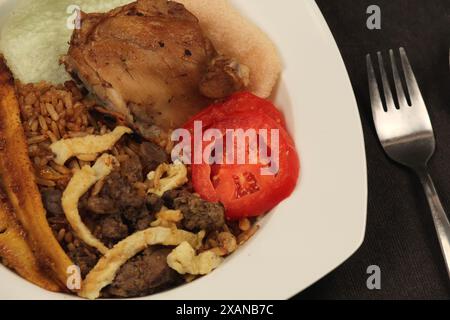 Nahaufnahme eines Tellers mit köstlichem Nasi-Goreng, gebratenem Krupuk-Kochbananen, Ei, Tomatenscheiben und Hühnerleber-Sambal. Stockfoto