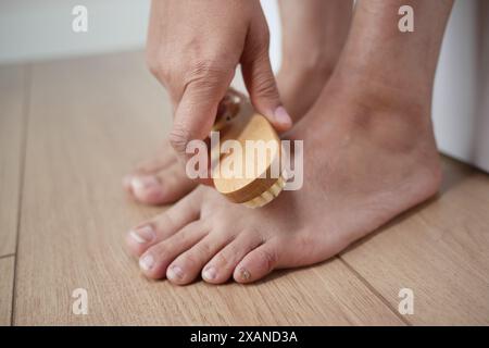 Mit einer Bürste bürstet die Person sanft ihren Fuß auf den Hartholzboden Stockfoto