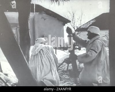 Screenshot des Zweiten Weltkriegs in Schwarzweiß. Deutsche Soldaten in Snow Camo feuern einen 8 cm großen Mörser ab. Die Besatzung stammt von einer Waffen-SS-Einheit. Stockfoto