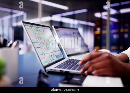 Afroamerikanerin, die ein virtuelles Dashboard verwendet, um neue Markttrends in der Finanzanalyse für ihr Unternehmen vorherzusagen. Stockfoto