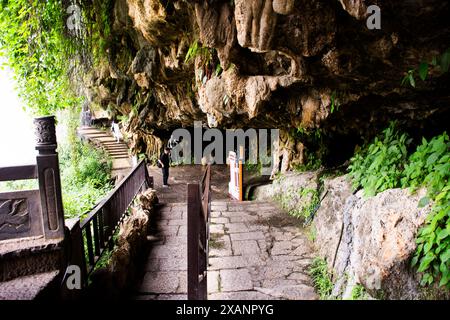 Chinesen und ausländische Reisende, die unter Wasserfällen spazieren, besuchen Sie archaische Menschen Neandertaler antike Statue in der Steinhöhle von Furong Zhen und T Stockfoto