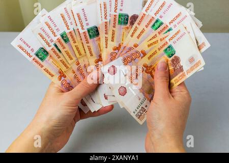 Eine Frau hält einen Haufen Geld in der Hand. Eine Million russische Rubel in Papiergeld in der Hand einer Frau. Bargeldeinsparungen in Russland Stockfoto