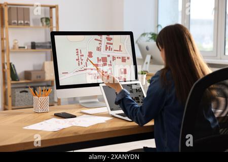 Kartograph arbeitet mit Katasterkarten am Tisch im Büro Stockfoto