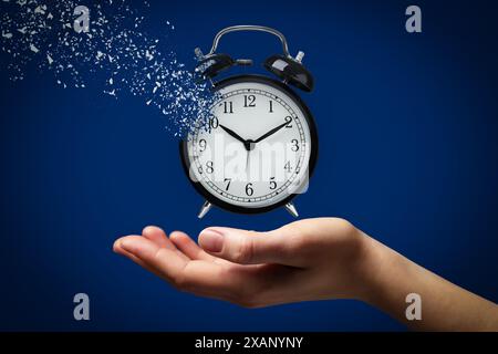 Die Zeit wird knapp. Frau mit auflösendem Wecker auf blauem Hintergrund, Nahaufnahme Stockfoto