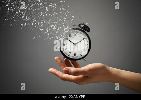 Die Zeit wird knapp. Frau mit auflösendem Wecker auf grauem Hintergrund, Nahaufnahme Stockfoto