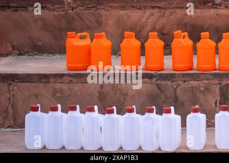 Farbenfrohe Plastikdosen in orangefarbenem Safran und weiß, die die traditionellen Gefäße zeigen, mit denen das Weihwasser vom ganga River gefüllt wurde, um es mit nach Hause zu nehmen Stockfoto