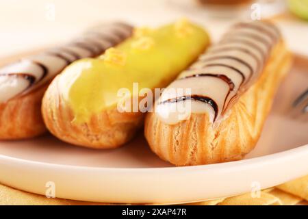 Teller mit verschiedenen leckeren glasierten Eclairs auf dem Tisch, Nahaufnahme Stockfoto