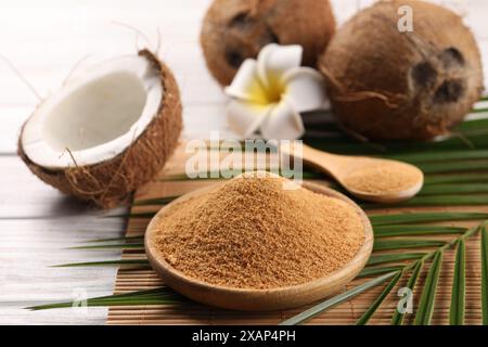 Kokoszucker, Palmblätter, Früchte und Bambusmatte auf rustikalem Holztisch, Nahaufnahme Stockfoto