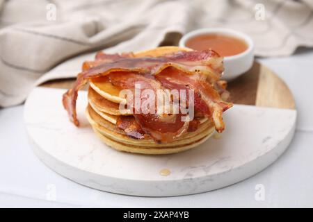 Leckere Pfannkuchen mit Speck und Honig auf weißem Tisch, Nahaufnahme Stockfoto