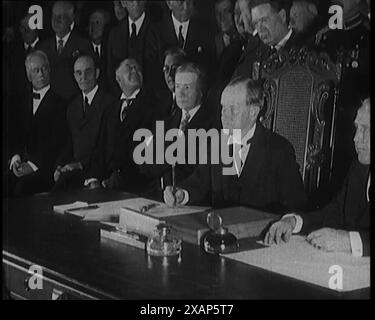 Frank Billings Kellogg sitzt neben dem amerikanischen Präsidenten Calvin Coolidge und unterzeichnet den Kellogg-Briand-Pakt, 1929. "...unterzeichnet [in Paris] von allen Nationen, die Kriege ein für alle Mal verbieten." Aus „Time to Remember – 1929 The Time of the House at Bognor“ – Reel 1; ein Dokumentarfilm über die Welt im Jahr 1929. Krankheit von König Georg V. &amp; wirtschaftliche Depression. Stockfoto