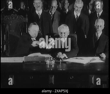 Frank Billings Kellogg sitzt neben dem amerikanischen Präsidenten Calvin Coolidge und unterzeichnet den Kellogg-Briand-Pakt, 1929. "...unterzeichnet [in Paris] von allen Nationen, die Kriege ein für alle Mal verbieten." Aus „Time to Remember – 1929 The Time of the House at Bognor“ – Reel 1; ein Dokumentarfilm über die Welt im Jahr 1929. Krankheit von König Georg V. &amp; wirtschaftliche Depression. Stockfoto