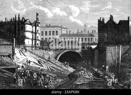 Kreuzung der St. John's Wood and Metropolitan Railways an der Baker-Street, [London], 1868. Eine Ansicht, die eine Vorstellung von der Lage des Durchschnitts des Bogens unter der Marylebone-Straße und der angrenzenden Gebäude, darunter das Marylebone Workhouse, gab es Schwierigkeiten beim Überqueren des Regent's Canal, wo die Linie mit einem Gefälle von eins zu sechzig steigen musste. Aber das war eine Kleinigkeit, verglichen mit dem Abwasser unter den Kanal auf einer solchen Höhe zu bringen, dass es immer innerhalb eines Yards vom Wasser darüber war. Die Arbeiten wurden durch den Antrieb von Eisenzylindern unter den Kanal durchgeführt. Stockfoto