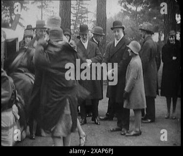 Eine zivile Frau, die einer anderen zivilen Frau hilft, einen Mantel vor einem Auto anzuziehen, und eine kleine Menschenmenge, 1920er Aus „Time to Remember – Teenage Flapper“, 1920er Jahre (Reel 4); ein Dkumentary über das Leben von Frauen in den 1920er Jahren – großartiger Kommentar von Joyce Grenfell. Stockfoto