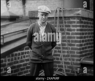 Männlicher Zivilist mit Strickjacke und Flatcap, stehend vor einer Wand, die vor der Kamera spricht, 1930er Jahre Kriminelles Geständnis: "Ich hatte noch nie Ärger." Aus Time to Remember - The Tough Guys, 1930er Jahre (Reel 1); ein Dokumentarfilm, der sich hauptsächlich mit dem Leben in Amerika befasst, das von Depressionen und Gangstern heimgesucht wurde. Stockfoto