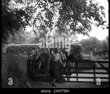 Wanderer, die über ein Tor klettern, 1933. Es war [in diesem hellen Sommer], dass sie das Wandern erfanden. Es war, als bräuchte das Gehen nach einem Jahrhundert mechanischen Antriebs einen neuen Slogan, eine neue Spielerei, um es zu verkaufen... der Sommer der großen Wanderungen, der Sommer der Treffen in der freien Natur, der Sommer der Wiederentdeckung, in Shorts und Hemden. Der Massenüberfall von Kindern Scout war ein Protest beim Kinder Scout im Peak District, Derbyshire, der am 24. April 1932 stattfand. Der Protest sollte darauf hinweisen, dass Wanderern der Zugang zu Gebieten mit offener Landschaft verweigert wurde, die zuvor fenc gewesen waren Stockfoto