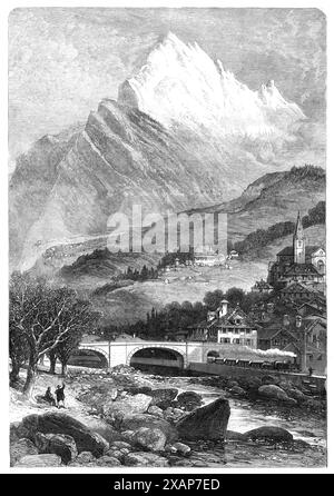 Die neue Überlandverbindung nach Indien: Mont Cenis Railway - St. Michel, 1869. "St. Michel... ist der Punkt, an dem die französische Eisenbahn durch Savoyen (heute gehört sie zur Pariser, Lyon und Mittelmeer-Kompanie, die die Victor Emmanuel-Kompanie übernommen hat) zu ihrem Ende ankommt; und hier beginnt die Mont-Cenis-Linie. Es liegt ein paar Meilen hinter St. Jean de Maurienne, der wichtigsten Stadt des Bezirks. St. Michel ist nur ein Dorf. In der Pfarrkirche, die wir sehen, mit ihrem spitzen Turm, befindet sich in den Reredos des Altars eine vollgroße Figur des heiligen Michael, mit einem Schwert in einer Hand und Stockfoto