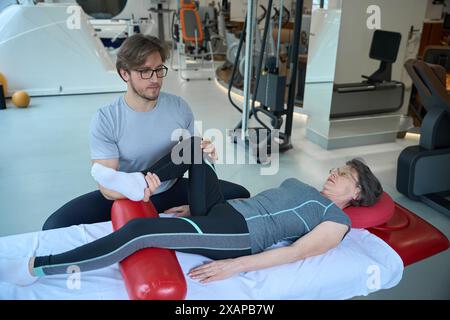 Junger Mann arbeitet an den Gelenken älterer Patientinnen Stockfoto