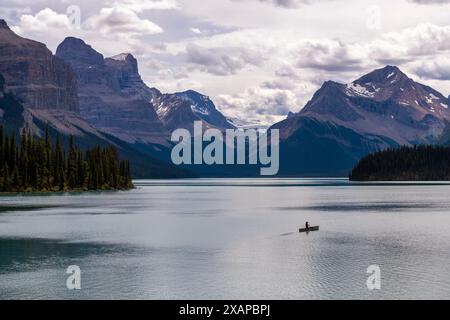 Ein Mann mitten in der Natur, in einem Kanu auf dem Maligne Lake, gesehen von Spirit Island, Jasper National Park, Kanada. Stockfoto