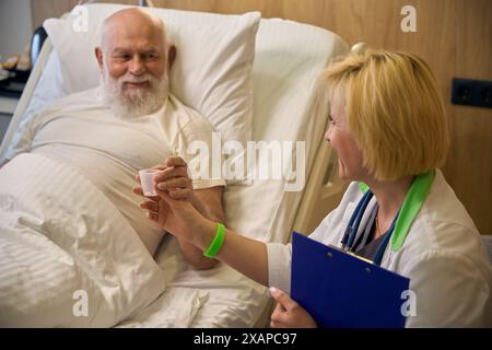 Der Erwachsene Patient liegt in einem Krankenhausbett und nimmt Pillen Stockfoto