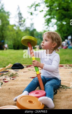 Kleines Mädchen, das mit Puzzlespiel spielt. Portraitbild eines 2-3 Kleinkindes. Glückliches Mädchen, das im Park das Plastikblöcke spielt. Stockfoto