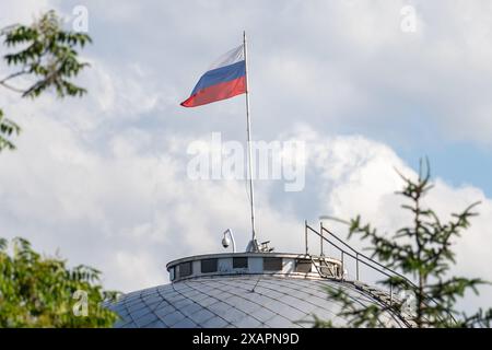 Die russische Flagge fliegt während der Kundgebung auf dem Dach der Botschaft. Pro-ukrainische Aktivisten organisierten einen Protest zum 1. Jahrestag des Bombenanschlags auf den Kakhovka-Damm durch Russland. Als Folge der russischen Gewalt, die die Europäische Union als Kriegsverbrechen bezeichnete, ertranken Tausende Ukrainer, Ökosysteme wurden zerstört und 700.000 ohne Trinkwasser. Um dieses Verbrechen zu gedenken, versammelten sich Demonstranten vor der russischen Botschaft in Warschau zu einer kleinen Aufführung. Ein Modelldamm und ein Dorf wurden gebaut und dann durch Wasser, das durch den Modelldamm fließt, performativ zerstört. Stockfoto