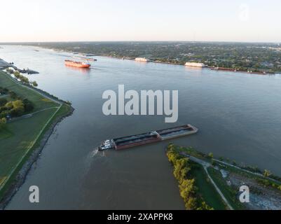 Aus der Vogelperspektive lässt ein Binnenschiff den Industriekanal in New Orleans' historischem 9th Ward verlassen und bei Sonnenaufgang in den Mississippi River eindringt. Stockfoto